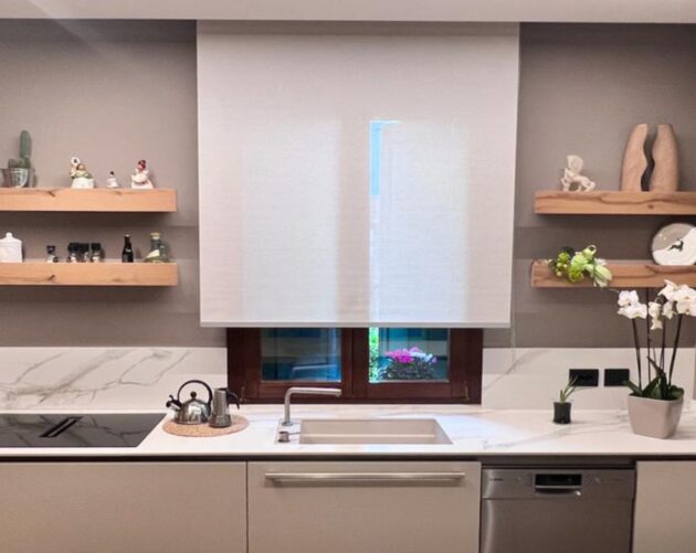 una tenda a rullo con tessuto poliestere e lino infiammato creata su misura e installata sulla finestra di una cucina.