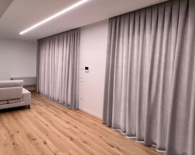 le vetrate di un salotto con due tendaggi oscuranti color tortora su misura all'arredamento